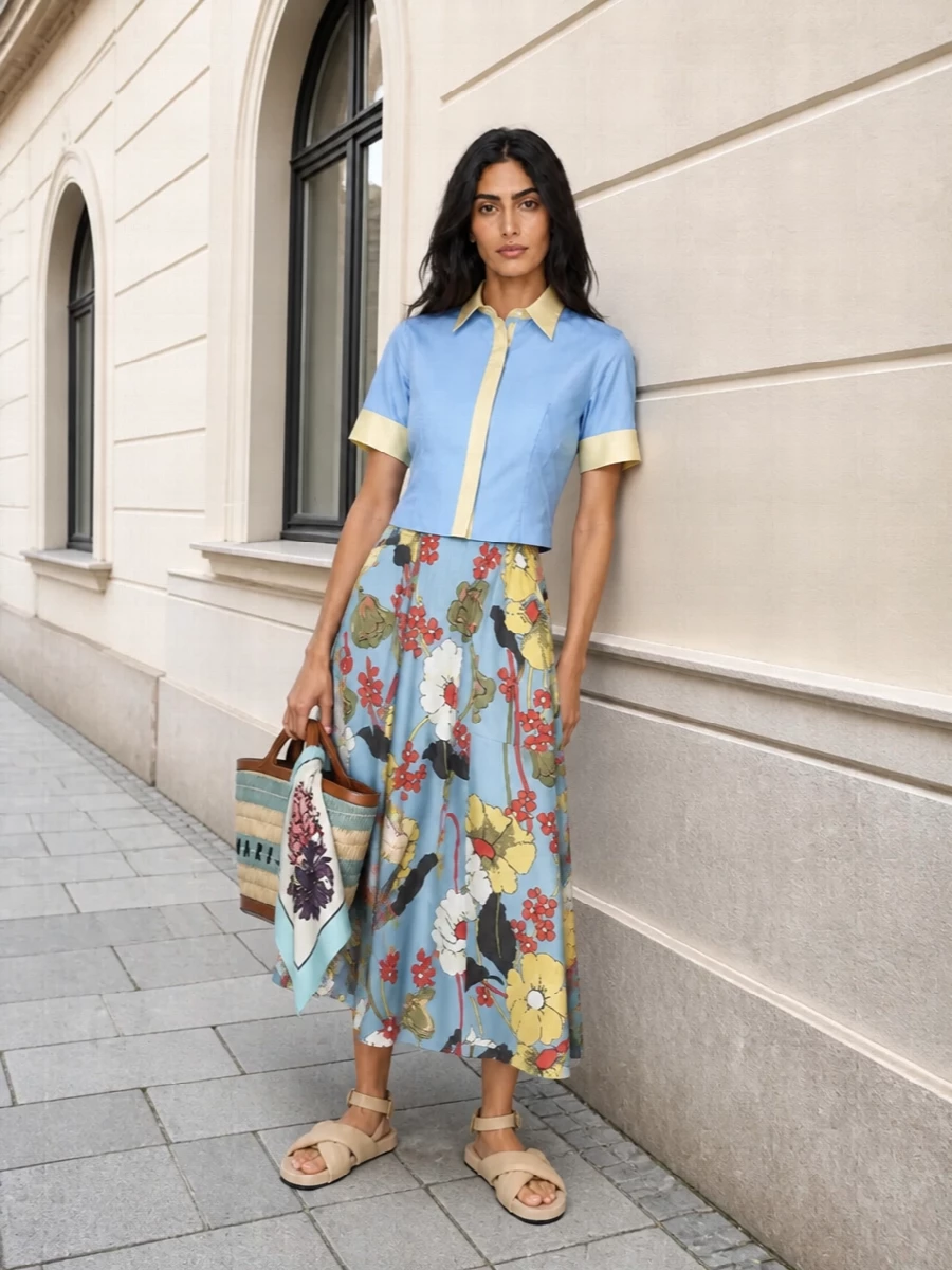 Powder blue and butter yellow anchor this Marni set in a clear, sunny palette, with the graphic floral skirt balanced by a clean, color-blocked, slightly cropped shirt. Soft beige padded sandals and a woven basket bag keep the mood relaxed and romantic rather than precious, perfect for city days or weekend lunches. Tie the silk scarf at your neck or bag handle to echo the florals in a softer, more polished register.