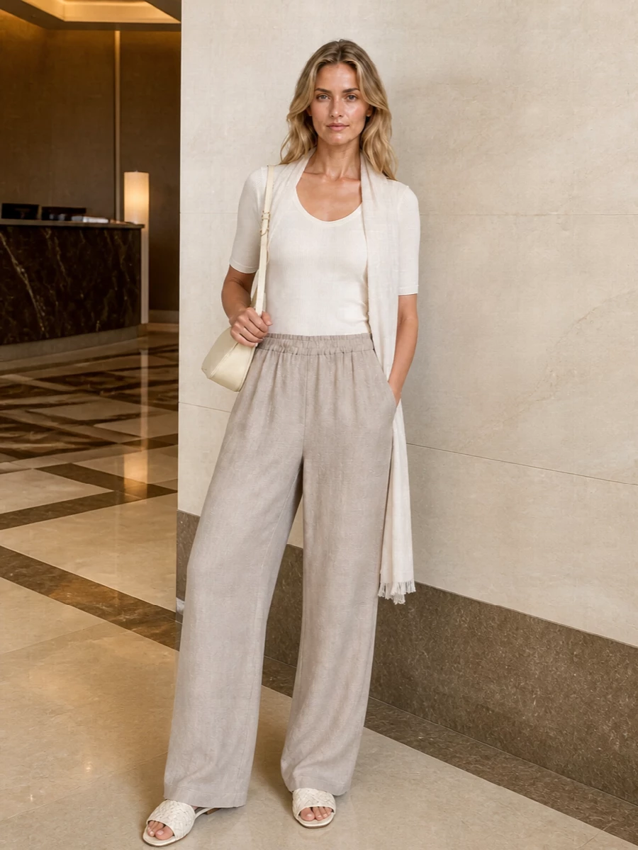 A warm ivory ribbed tee meets fluid taupe wide-leg trousers for a soft, elongated line that feels calm and assured. Cream slides and a buttercream shoulder bag keep everything in the same hushed neutral family, so the focus stays on proportion and ease. An airy ivory wrap adds just a hint of texture for days when you want subtle depth without breaking the palette.