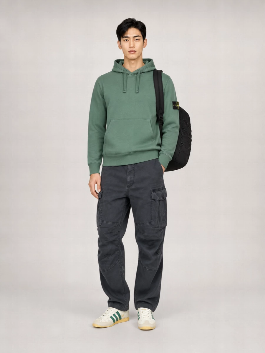 Muted forest green sits against washed charcoal and off-white, giving a calm, technical streetwear energy that still feels pulled together. Relaxed cargos, terrace-leaning sneakers, and a padded backpack keep it ready for city days, from commute to late-night wanderings. The mix of workwear hints and sport details keeps the whole outfit grounded without trying too hard.