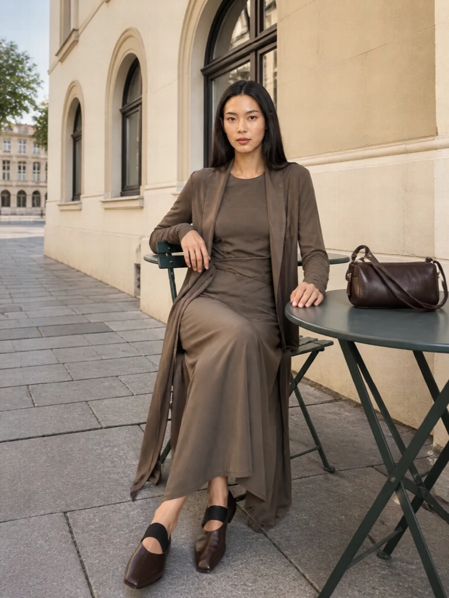 I am keeping this all about a long, uninterrupted column of taupe and deep brown, letting the wrap coat and fitted dress read as one continuous, sculpted line. The pointed flats and slim chocolate shoulder bag stay low-profile and directional, so the drama comes from proportion and movement rather than hardware or contrast.