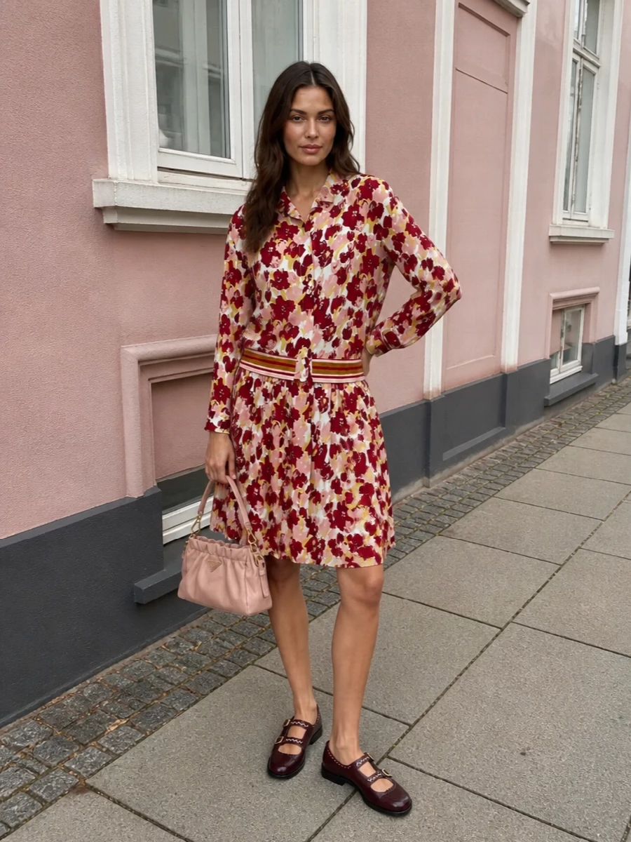 Head-to-toe Marni florals in burgundy, blush and butter yellow read like a modern co-ord, with the pleated skirt echoing the blouse’s painterly romance while the striped hem keeps it sporty and sharp. Burgundy Mary Jane mules anchor the palette and lean into the preppy mood, while the blush Prada shoulder bag and Ferragamo silk scarf bring a softer, ladylike finish. The result is an artful spring ensemble that feels playful yet composed for gallery days, lunches or early-evening drinks.
