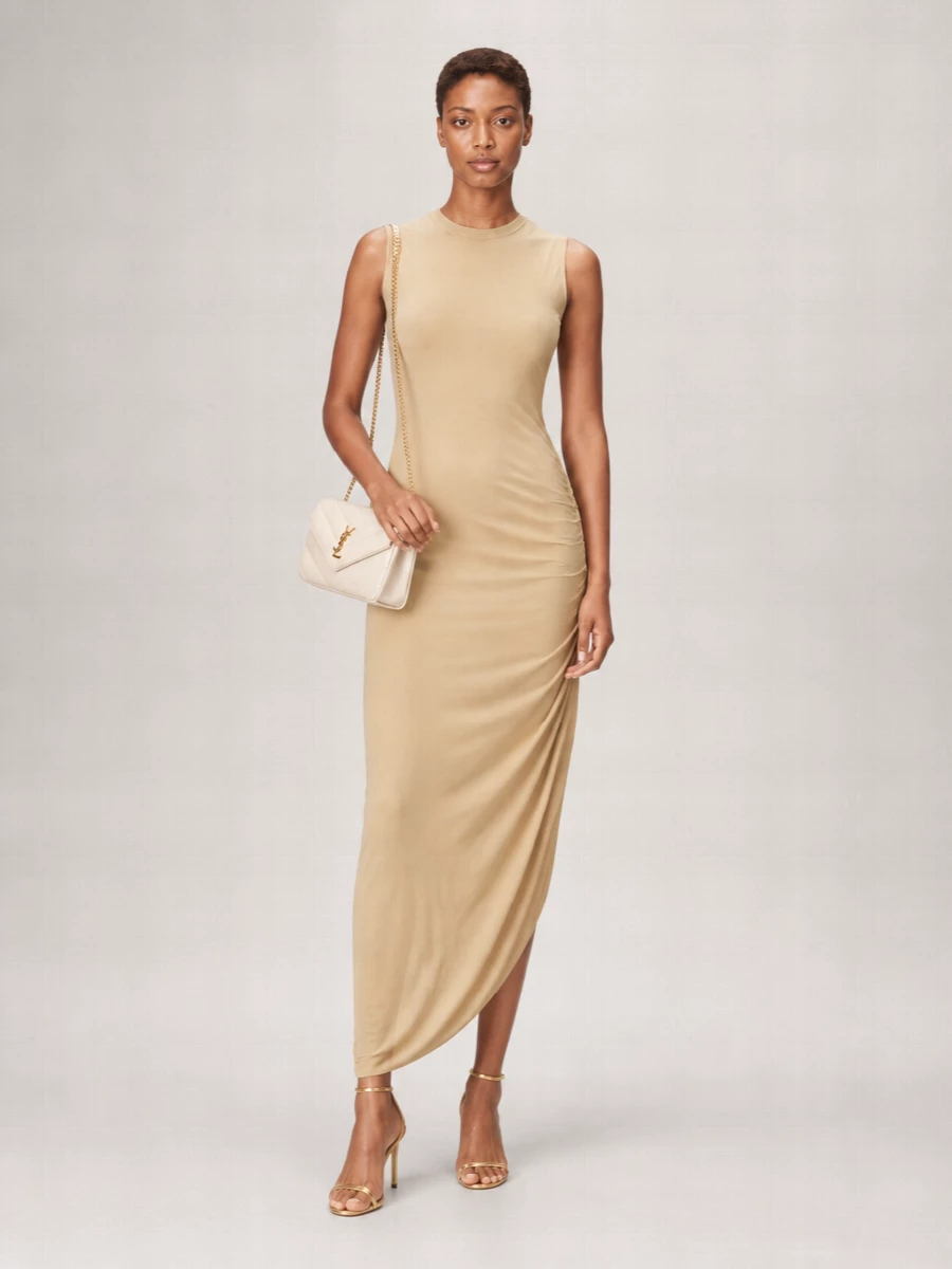 The Jean Paul Gaultier camel midi and Saint Laurent cream bag create a quietly sculptural, monochromatic base that feels modern and restrained. Metallic gold sandals introduce just enough shine to nod to the bag’s hardware without competing with the clean lines. Choosing the dress route over separates keeps the silhouette long and uninterrupted, which flatters the structured small shoulder bag and suits refined summer dinners or gallery evenings.