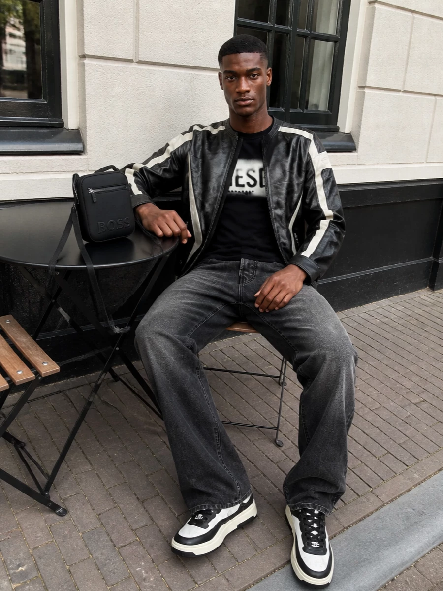 This is graphic Diesel streetwear built around that sprayed leather jacket, grounded with a washed logo tee and lived‑in straight black denim. Chunky two‑tone sneakers and a clean black crossbody keep the palette tight and the attitude unapologetically downtown without feeling forced.