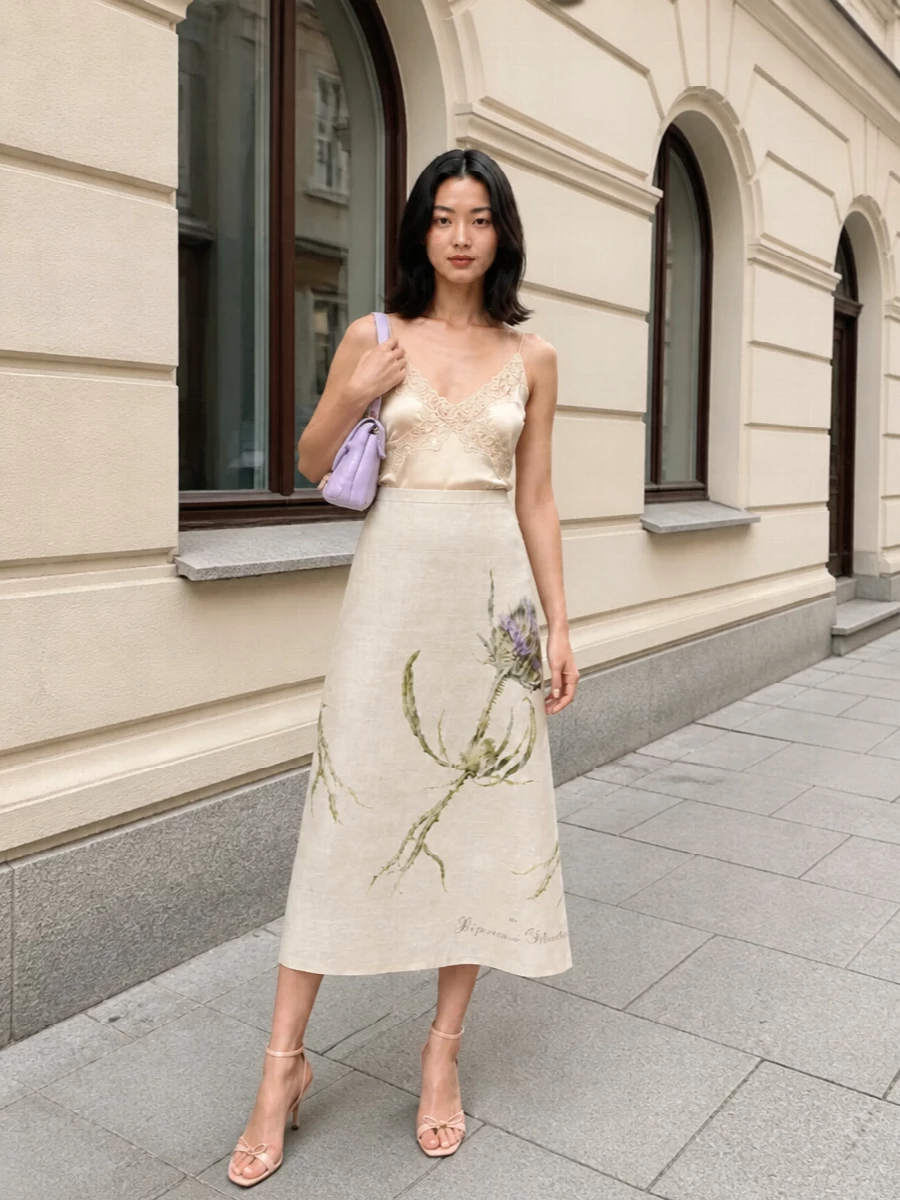 A champagne satin camisole and the high-waisted floral midi create a soft, romantic column of light that feels perfect for garden parties or terrace dinners. Blush-nude strappy heels keep the line elongated and delicate, while a pastel lilac clutch and gauzy floral stole add just enough colour and texture to feel intentional yet quietly polished.