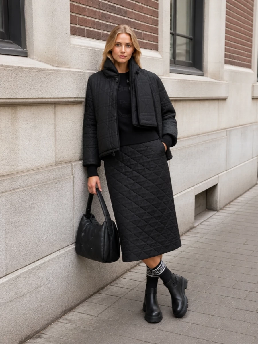 I am deliberately building this around separates rather than a dress, so the quilted Dior coat can play against a structured knit and skirt instead of fighting a one-piece line. The result is a monochrome, texture-led city uniform: Dior on top and toes, Jil Sander defining the straight skirt line, and Margiela adding a single intellectual note with a padded shoulder bag. It feels quietly directional and practical for cold days, with subtle branding and quilting doing all the talking.