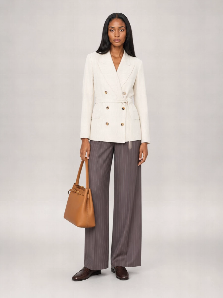 Cream pinstripe tailoring meets fluid taupe wide-leg trousers for a softened take on power suiting. Burnished loafers and a caramel top-handle keep the palette warm and considered, while a nude belt quietly sharpens the waist. The result is office ready yet relaxed enough to carry into dinner without a change of tone.