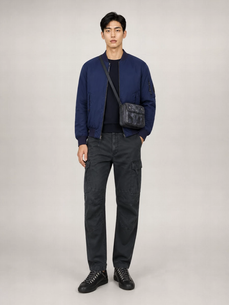 A navy-on-navy upper half with the C.P. Company bomber and Diesel crew keeps the outfit streamlined and quietly technical. Washed-charcoal cargos, black leather sneakers and a structured camo crossbody add practical edge without breaking the muted palette. The result is a winter-ready, city-focused uniform that moves easily from commute to weekend.