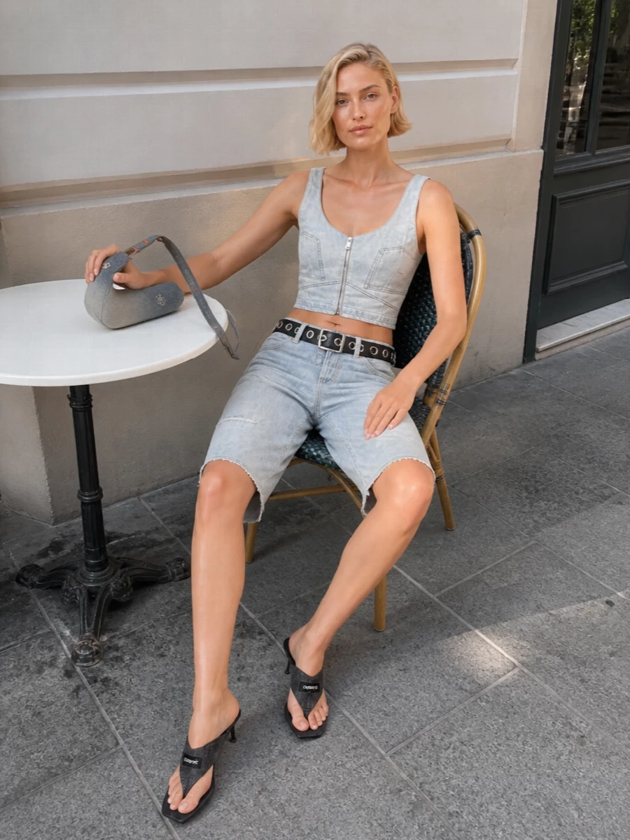 Ultra-faded Haikure denim on top and bottom reads like a deconstructed two-piece, with the built-in belt giving just enough grit. The Coperni thong mules and sculptural Diesel shoulder bag keep the palette tight in greys and black while pushing the vibe toward night-out city energy. A studded Attico belt ties the hardware together for a sharp, Y2K-leaning finish that still feels easy for high-summer streets or festivals.