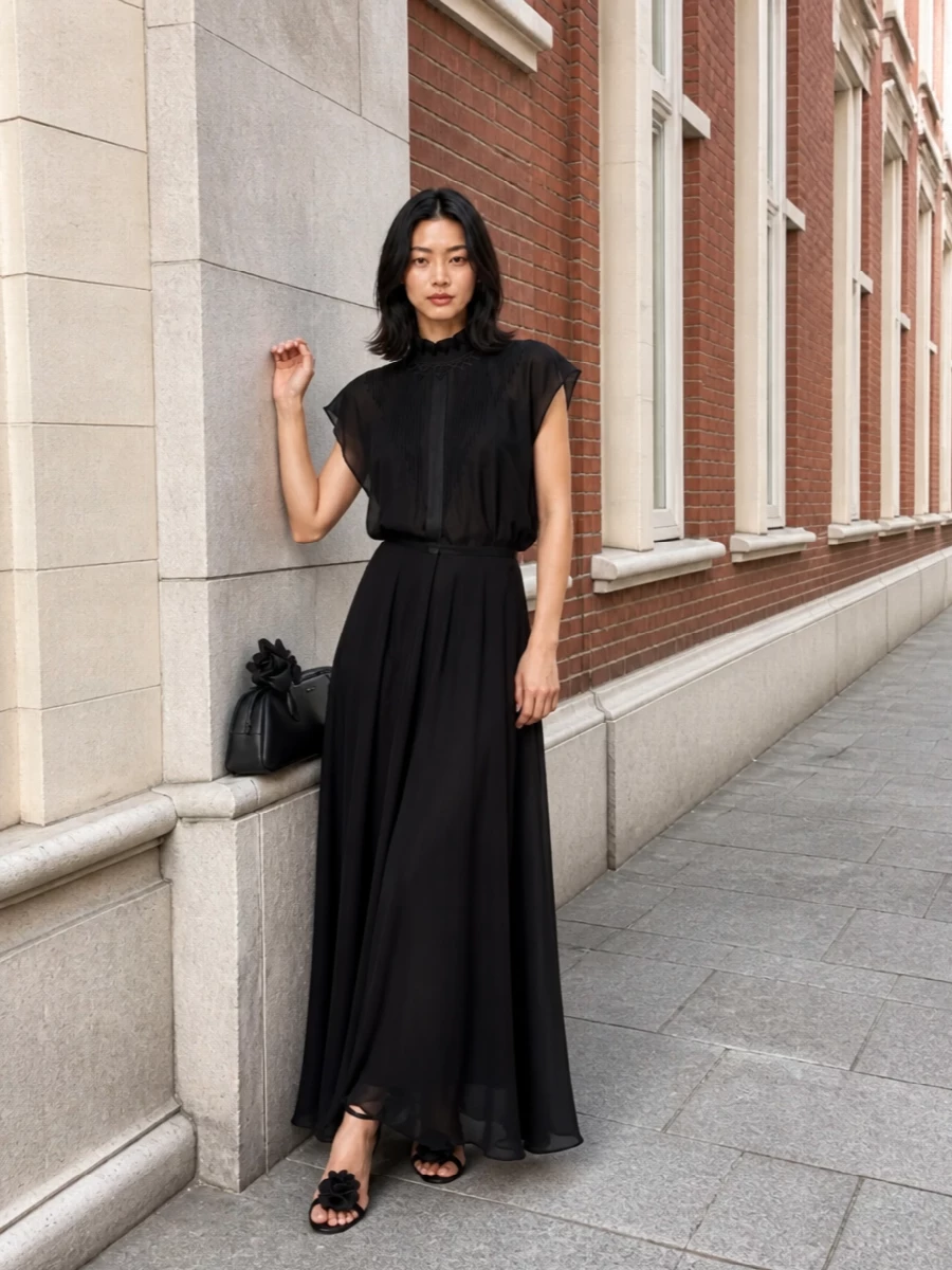 A fluid black Fendi column gown is paired with sculptural Magda Butrym roses at the foot and hand, keeping the palette inky and the romance quietly charged. The repetition of floral details reads intentional and couture-like, while the clean lines and high stiletto keep the silhouette long, sleek and evening ready.