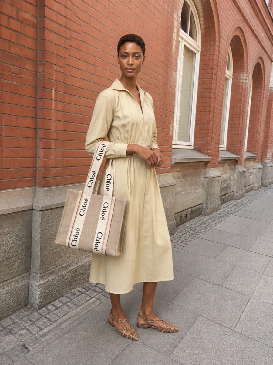 Opting for the shirt dress path keeps the Chloé tote front and centre, playing up its relaxed Parisian utility against a similarly easeful Max Mara silhouette. The light beige dress and sand-toned woven flats sit in the same warm-neutral family as the bag, creating a soft, sunlit palette that feels city-ready yet quietly bohemian. Texture stays gentle and natural, so the logo straps read considered rather than loud, perfect for warm days that stretch from errands into dinner on a terrace.