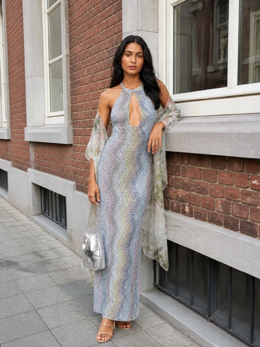 For summer cocktails or a seaside wedding, this Missoni crochet halter dress is framed with champagne-gold spiralled sandals and a petite silver evening bag for light-catching movement. The metallic accents stay delicate so the chevron knit and soft silver-blue tones remain the story, while a gauzy floral wrap introduces a whisper of sage and blush if you want an extra romantic layer. The result is long, lean and fluid, with just enough sparkle to feel special after dark without reading overdone.