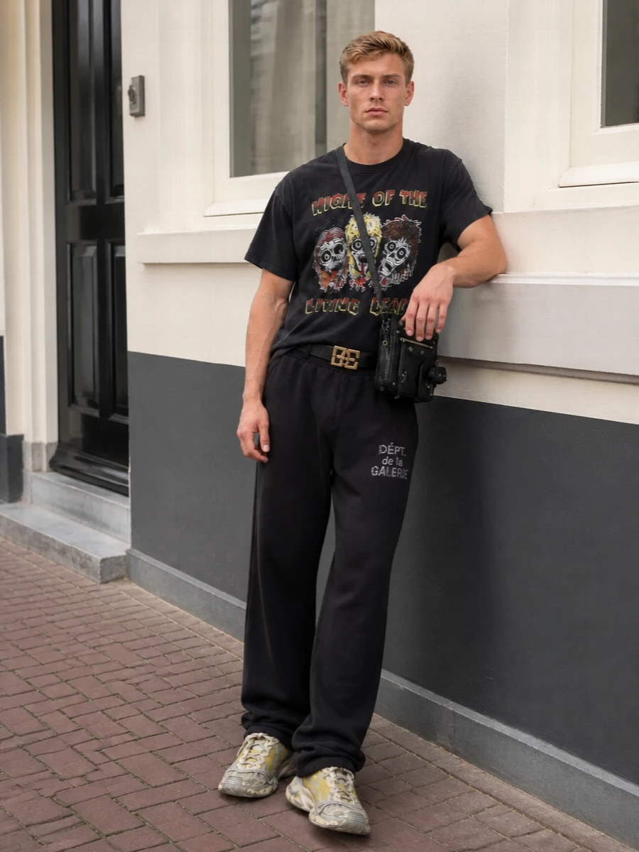 A horror-punk Gallery Dept. tee sits over relaxed black track pants for a slouchy, backstage silhouette that keeps the focus on the graphic. Distressed acid-tinged Balenciaga runners pick up the yellow in the print, while a hard-edged moto crossbody and sharp logo belt bring just enough structure and polish to make the whole thing feel intentionally styled, not thrown on. It is a late-night, venue-hopping uniform that balances nostalgia with current luxury streetwear codes.