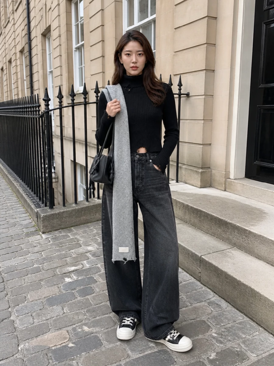 Distressed rib and strong denim volume set a moody, off-duty foundation in deep black and washed charcoal. Graphic high-top boots keep the proportions grounded and urban, while a slim black shoulder bag and quietly subversive scarf finish the mix with just enough polish.