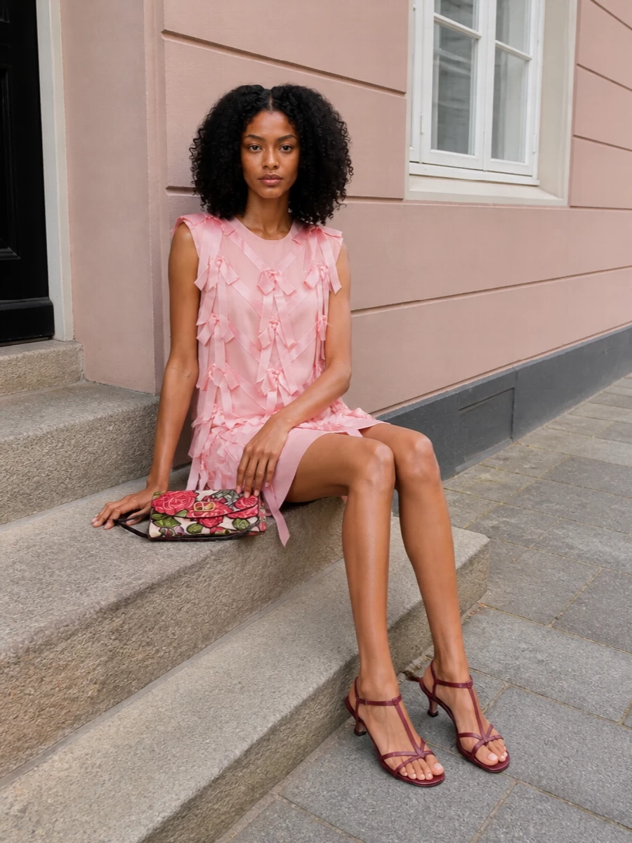 This pairing lets the Valentino floral clutch sing against Prada’s blush bow dress, keeping the romance focused on soft pinks and sculpted detail rather than busy print. The Jil Sander wine slingbacks ground the sweetness with a subtle, grown-up contrast, their slender straps echoing the bag’s hardware for a cohesive, quietly glamorous evening ensemble. I chose the dress route here so the bag’s embroidery and the bow work in tandem, rather than competing with separate top-and-skirt proportions.