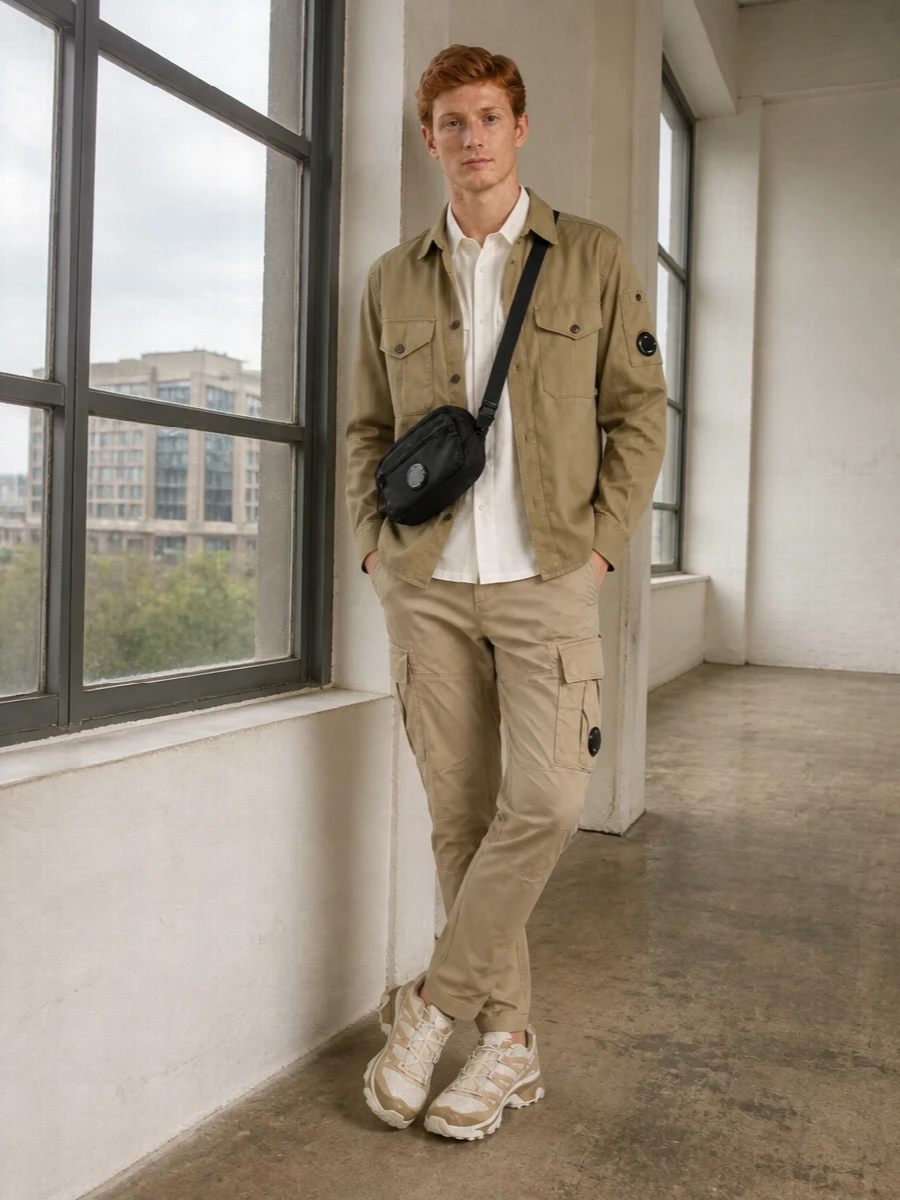 Khaki utility layers sit against sand cargos and clean white, giving a calm, technical streetwear uniform that still feels light for warm days. Neutral Salomon runners and a compact black crossbody pull everything into a streamlined, city-ready palette. The mix of tailored taper and boxy top keeps the silhouette contemporary without reading try-hard.