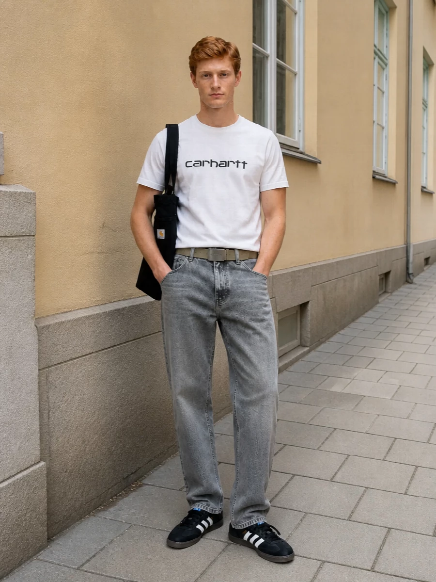 Soft monochrome layers keep the Carhartt WIP tee grounded, pairing best with washed grey straight-leg denim and black terrace sneakers for a clean streetwear uniform. The black canvas tote and sand webbing belt add practical workwear touches without breaking the muted palette.