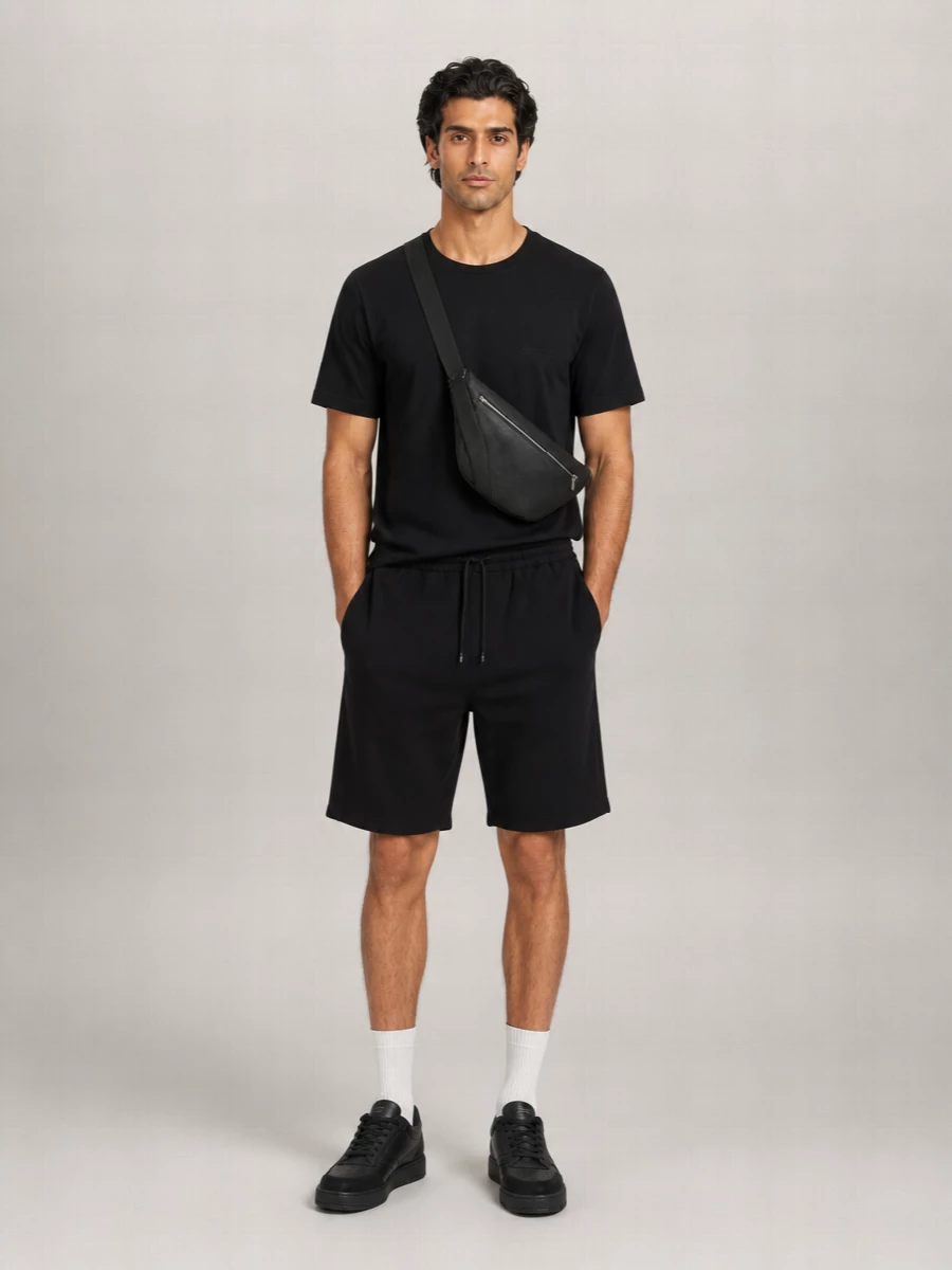 A monochrome black story keeps the Saint Laurent shorts sharp rather than basic, anchored by a quietly branded Givenchy tee and low-profile leather sneakers. The clean lines, subtle logos and compact crossbody lean into modern streetwear while still reading polished for city days and low-key nights. It is an easy uniform that feels intentional from head to toe without trying too hard.