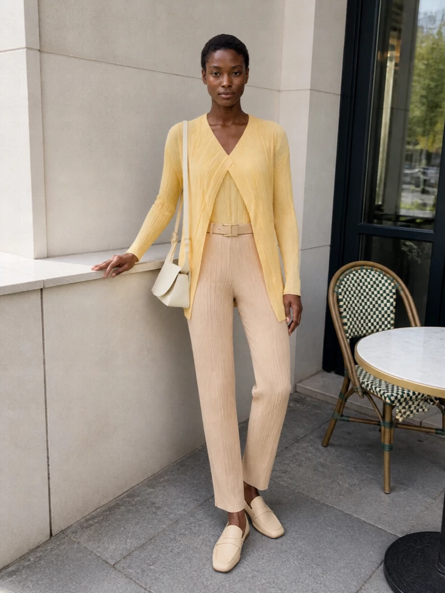 A tonal pleated column in soft beige and citrus yellow sets a calm, sculptural base that reads modern rather than sweet. Butter-toned loafers and a slim cream belt keep the line clean and unfussy, while the structured buttercream shoulder bag adds just enough architecture for desk, gallery or dinner. The result is a quietly confident neutral story with a gentle wash of colour and movement.