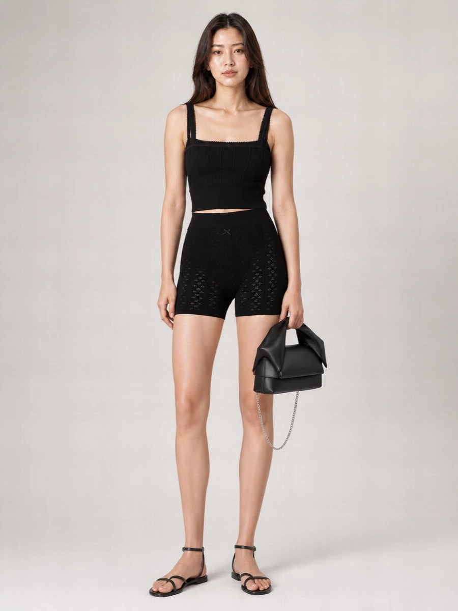 A modern knit co-ord in inky black turns loungewear intimacy into a city-ready uniform. The fitted camisole and matching high-waist short trace a long, lean line, while barely-there sandals and a compact top-handle bag keep everything light and precise for warm days out. It feels soft and close to the body, but the monochrome palette and clean accessories keep it firmly in quiet-luxury territory rather than at-home only.