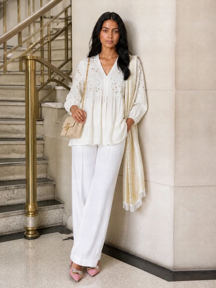 An ivory broderie tunic meets sharp white tailoring for a soft, elongated column that still feels relaxed. Blush-toned slingbacks and a cream Love Birds bag bring gentle romance without tipping into overt occasionwear. A tonal paisley stole finishes it with a barely-there boho nod that suits both city terraces and seaside dinners.