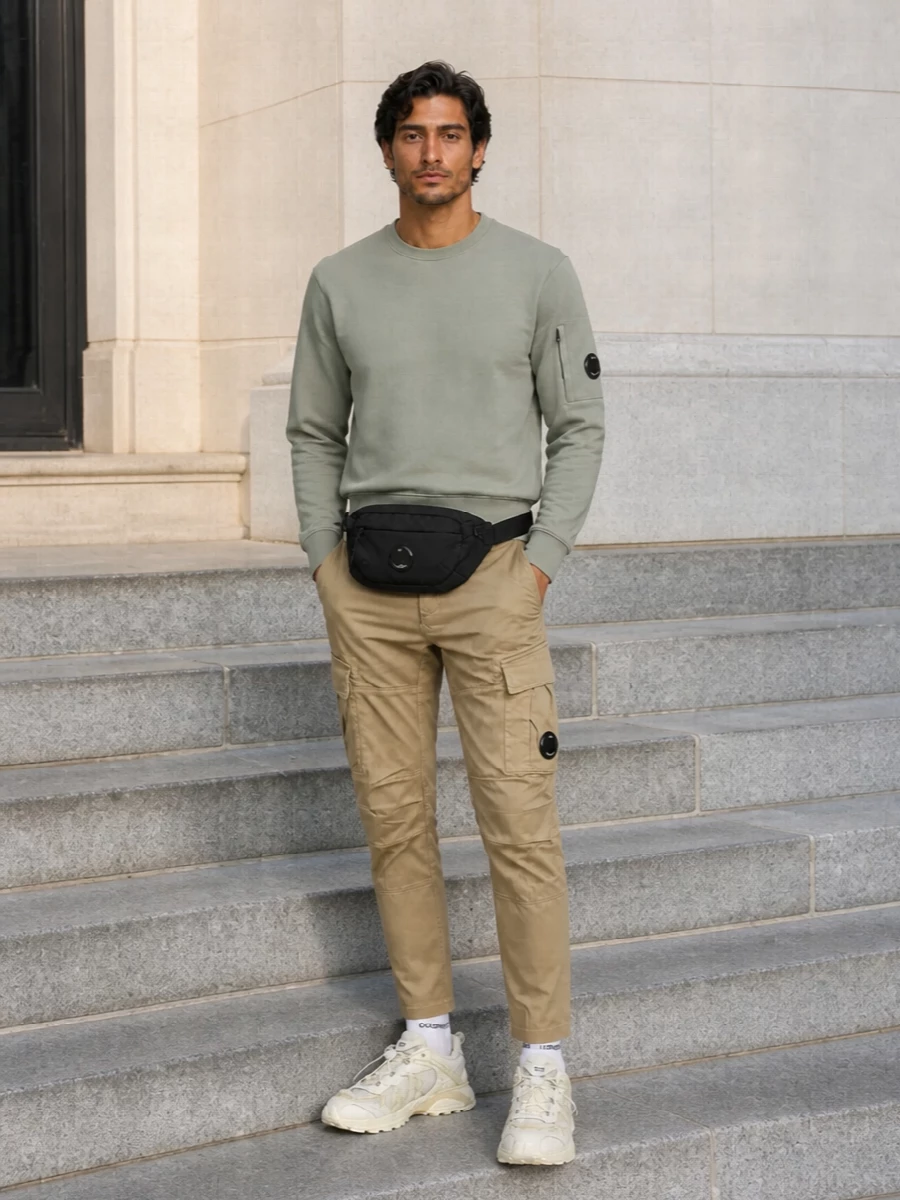 Soft sage on top and sand below keep the palette light and technical, with C.P. utility details linking every piece. The tapered cargos and streamlined runners stay sharp without feeling tight, and the black belt bag plus socks finish things with just enough contrast for real city wear.