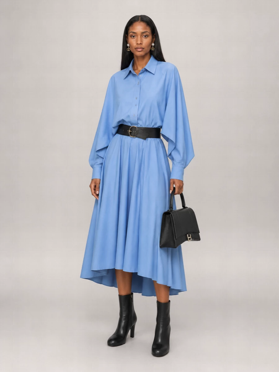 Powder blue tailoring stays soft but intentional here, cinched cleanly at the waist and grounded with sharp black accessories. The stiletto ankle boots and structured top-handle keep the volume of the skirt controlled, while pearl-drop studs add just enough light at the face. It reads modern and composed, ready for a long city day that finishes at a good restaurant.