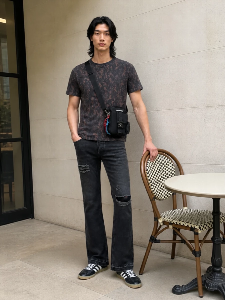 Washed black flares meet a grungy Adidas graphic tee for a gig-ready, street-sport mix that feels straight out of the pit. Black terrace trainers keep the silhouette lean and agile, while the technical crossbody brings hands-free utility and a touch of color without breaking the dark, lived-in palette.