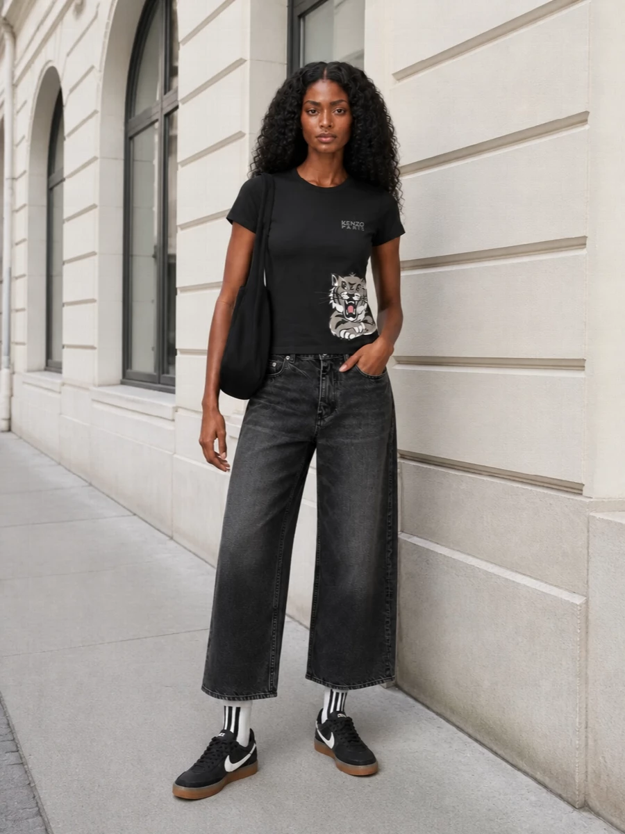 A graphic Kenzo tee sits over soft washed-black wide-leg denim for a street-clean silhouette with real presence. Monochrome Nike sneakers and a low-key Alexander Wang shoulder bag keep the focus on shape and logo detail, while striped socks add a subtle sport nod. It is a city-ready mix of relaxed volume and sharp branding that works from day errands to late casual hangs.