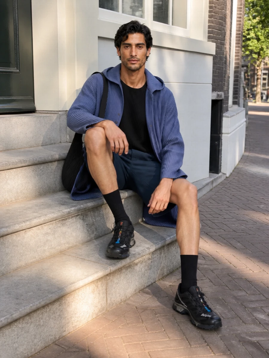 A head to toe pleated story in slate and black, this pairing leans into Homme Plissé’s sculptural volume then grounds it with precise tailored shorts. Technical Salomon runners and a pleated crossbody keep it urban, fast and light, ideal for city days that move from pavement to gallery to late dinner without a change.