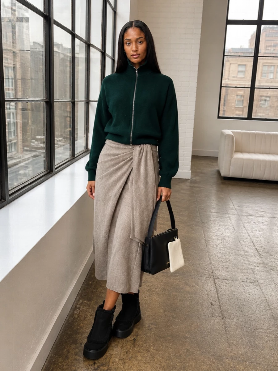 I’m styling this as a knit dress story, not top and bottom, so the Max Mara taupe wrap midi becomes the soft, elongated base under your forest green Extreme Cashmere zip jacket. The high necks and close, wrapped waist keep the silhouette long and clean, while the black chunky Gianvito Rossi boots and graphic Jil Sander shoulder bag sharpen the cocooned textures into a city-ready, quiet-luxury uniform. It feels warm, tactile and indulgent, but the palette stays disciplined in green, taupe, black and ivory so it never tips into lounge.