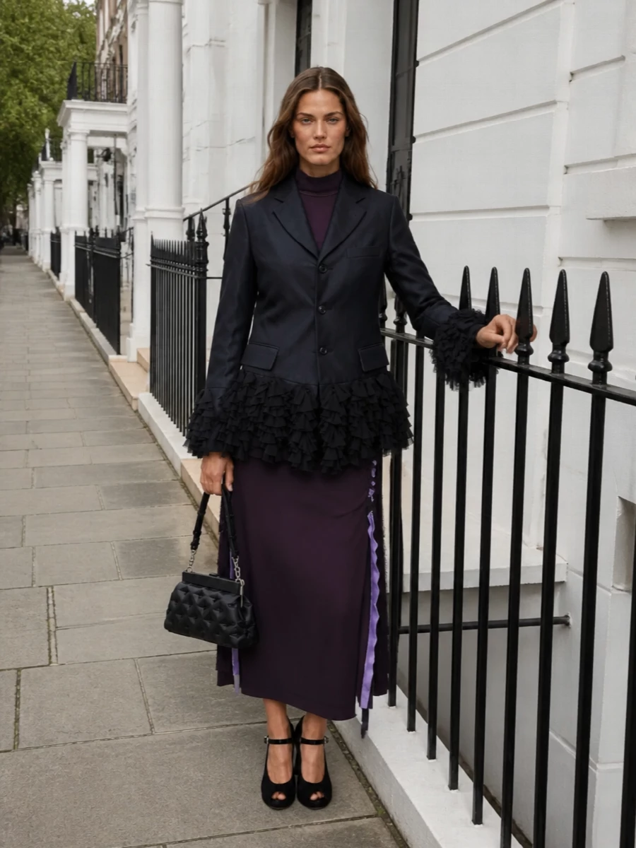 I’m treating the Comme des Garçons blazer as the evening statement layer and anchoring it with a Margiela plum midi dress so the ruffled hem reads intentional, not chaotic. The velvet Mary Janes and quilted frame bag stay in the same conceptual, romantic register, giving a coherent art-opening-to-late-dinner ensemble that is tailored, dramatic and entirely grown-up.