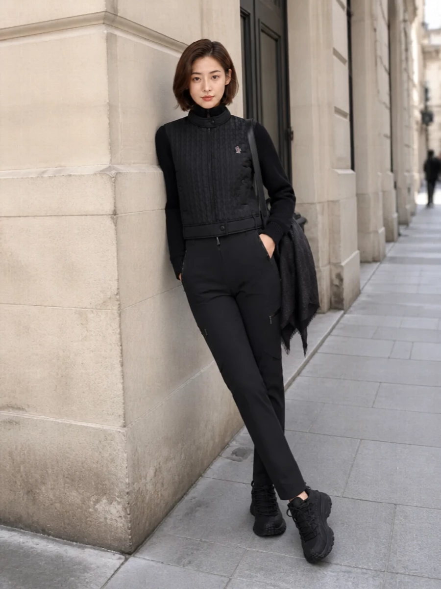 This look leans into a monochrome alpine-urban attitude: straight-leg technical cargo trousers paired with the quilted-front black Moncler zip cardigan for a clean, insulated silhouette. All-black trail sneakers keep the line sporty and grounded, while the sculptural Coperni oval backpack and a charcoal Gucci scarf sharpen the ensemble into a polished, performance-driven city uniform.