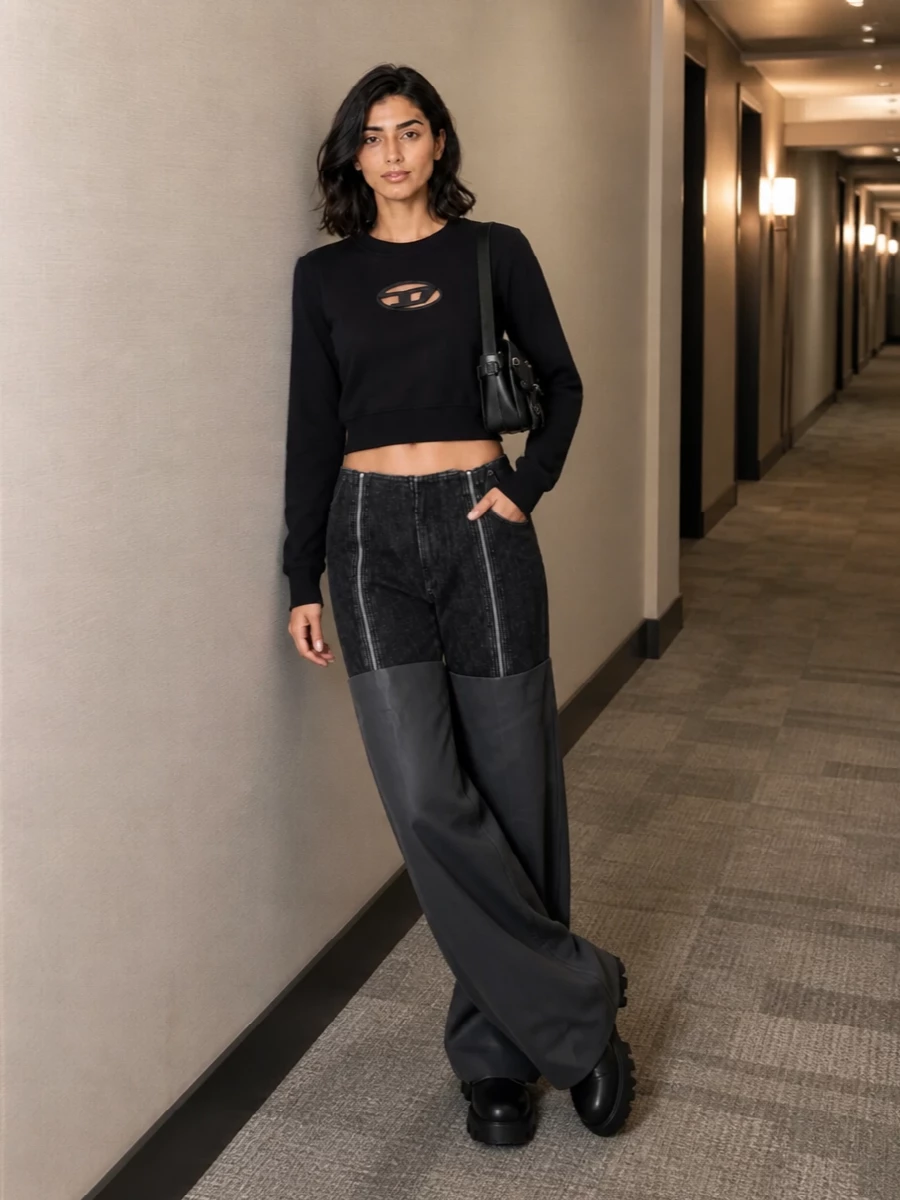 This is a nightlife-heavy, y2k-leaning streetwear set built around stark black and graphic hardware. The cropped logo top and exaggerated Gaultier pant create a sharp torso-to-volume contrast, grounded by tanky moto boots. A small black shoulder bag finishes it with just enough polish while keeping the mood firmly club-ready and urban.