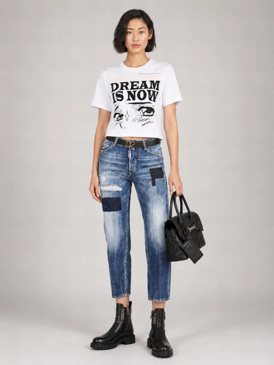 A graphic Dsquared2 tee and patchwork denim sit high on the waist for a clean, leg-lengthening streetwear line. Chunky black hardware boots and a structured black satchel sharpen the mood without tipping into formality. The logo belt quietly connects the dark accents, keeping the whole outfit cohesive and city ready.