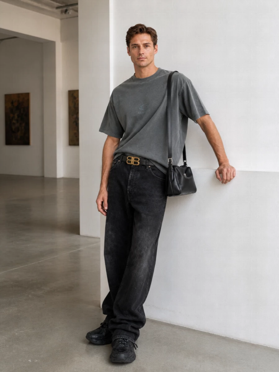 Slate and washed black keep this Balenciaga outfit firmly in that studio‑artist, off duty space, with the boxy tee and pooled denim sharing the same worn‑in attitude. The ultra textured runner and structured crossbody sharpen the silhouette, so the volume feels intentional rather than sloppy. A single gold belt buckle is the only shine, reading like a quiet signature rather than decoration.