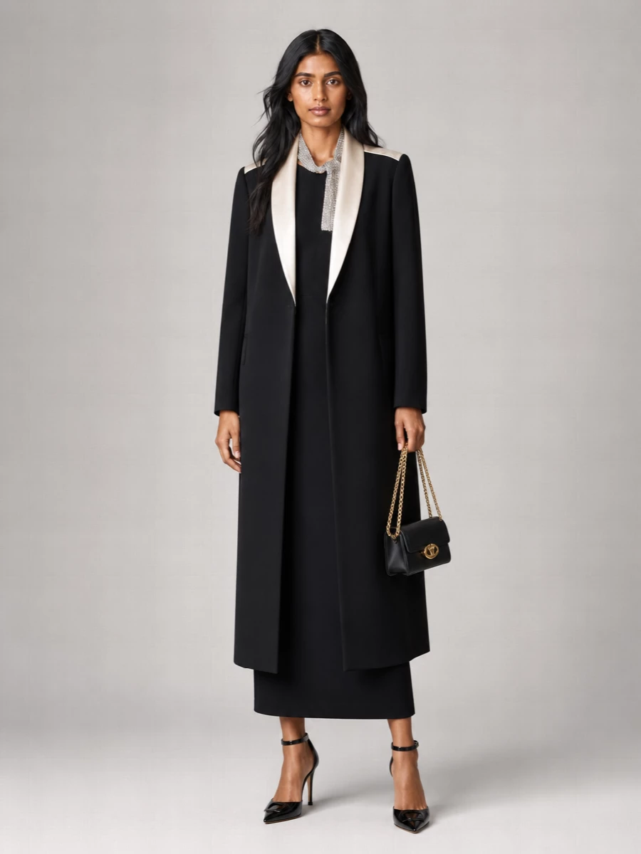 With the Valentino coat as a graphic tuxedo shell, the crystal‑tie column dress is the most coherent anchor, keeping the story formal, elongated and monochrome with champagne accents. A sharp ankle‑strap pump and compact gold‑hardware bag keep everything firmly in the evening, polishing the silhouette without interrupting the clean black lines. The result is a quietly commanding winter cocktail ensemble where the only shimmer comes from the neck and hardware, not competing layers of tailoring.