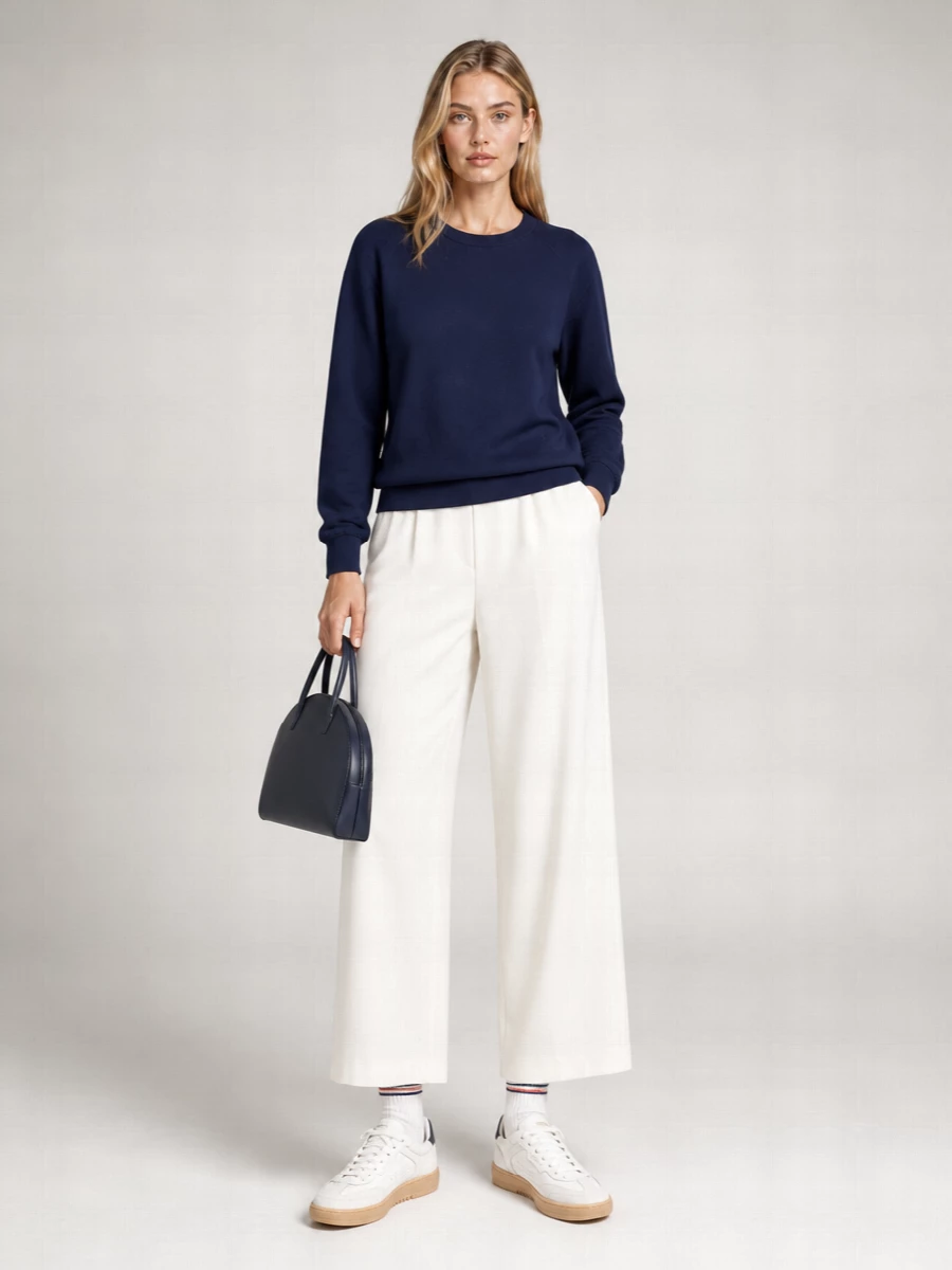 Navy and off-white keep this outfit calm and precise, with the wide-leg trouser giving the relaxed sweatshirt a cleaner, longer line. Low-profile white sneakers and an inky structured bag keep everything in a quiet, city-ready register. It feels easy for daytime but considered enough for anywhere you want polish without effort.