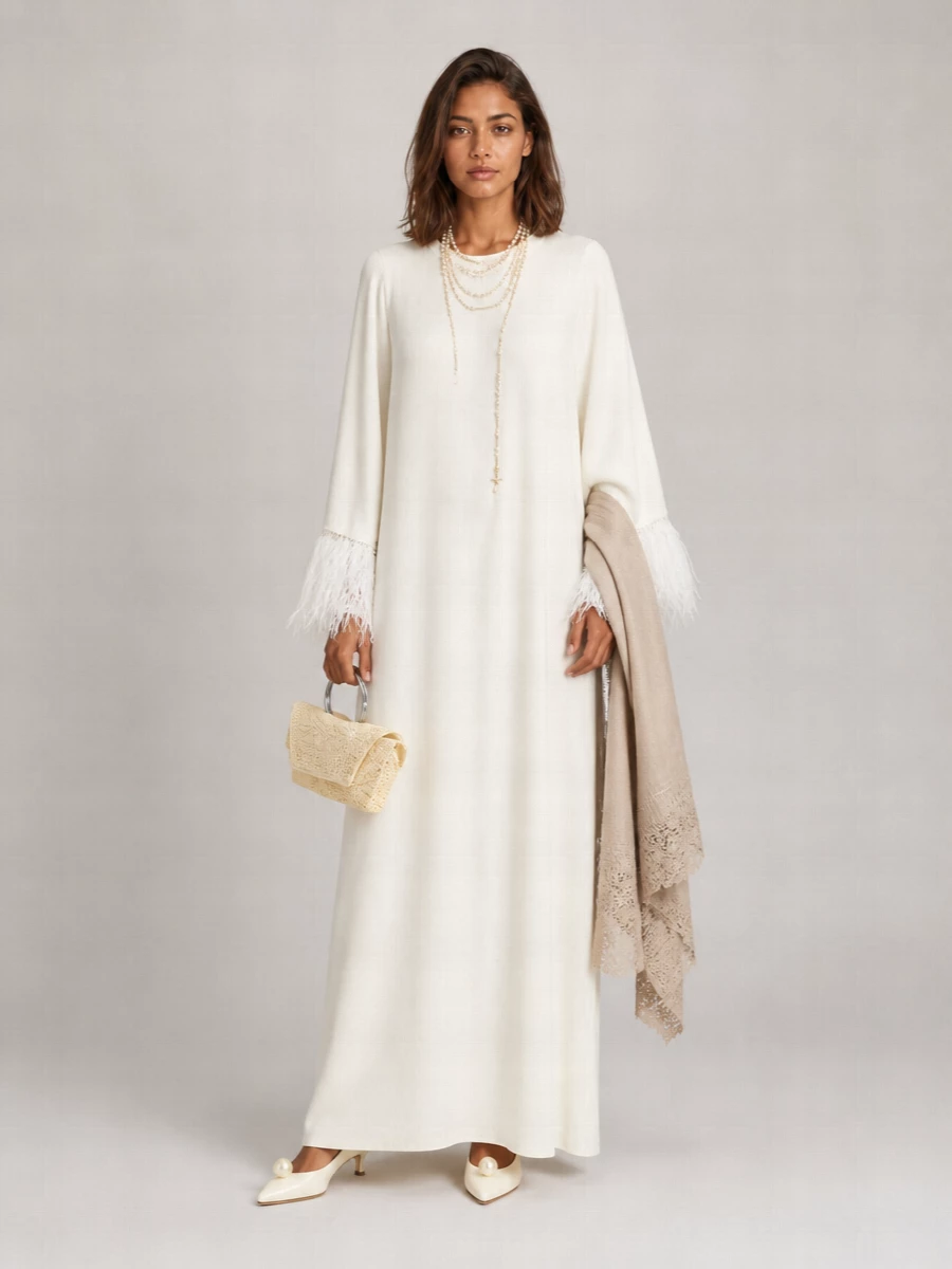 An ivory story in soft focus, this ensemble keeps the volume long and relaxed with just enough structure at the heel and hand to feel considered. Pearls, lace and gentle kitten height bring intimacy and romance, perfect for evenings that blur the line between at-home indulgence and quiet hosting. Every element stays within a hushed neutral palette so the feather-trimmed maxi remains the serene centrepiece.
