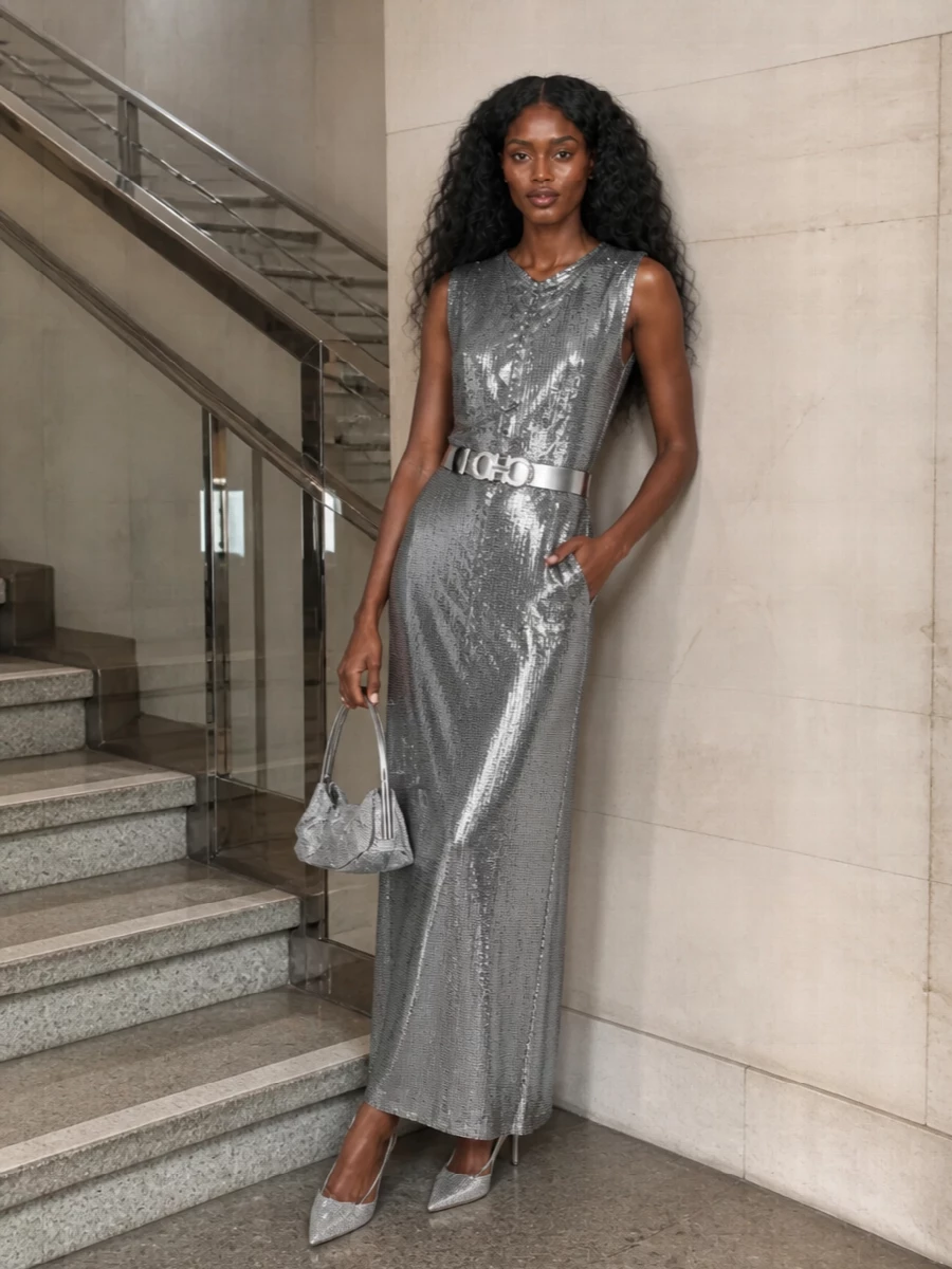 A pure metal column of silver catches every shard of light, cinched just enough at the waist to trace the body without interrupting the line. Crystal-sprayed slingbacks and a liquid-silver minaudière keep everything in the same mirrored palette so the dress reads as armour, not costume. It is a high-drama, night-only ensemble that feels sharply controlled in silhouette and unapologetically luminous in finish.