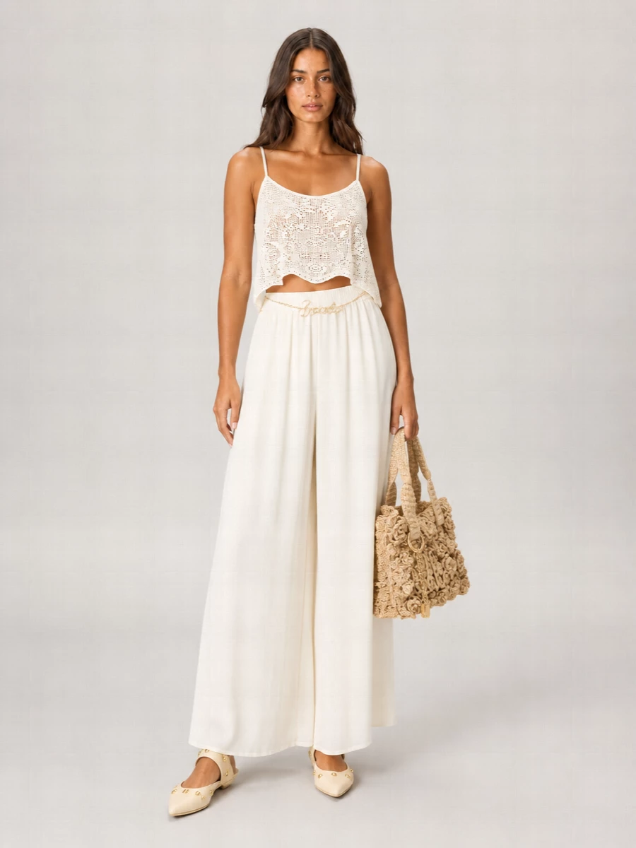Soft ivory layers create a long, fluid column that lets the crochet cami feel romantic rather than overtly beachy. The wide-leg trouser and pointed flat keep proportions elegant and relaxed, while raffia texture and a slim gold chain belt lean into Chloé’s sun-washed, bohemian ease for dinners by the water or city evenings in warm weather.