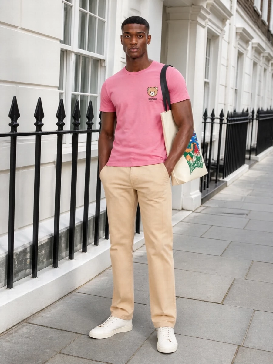 Dusty pink and warm beige keep this Moschino combo soft, clean and easy for daytime. Straight-leg chinos and pared-back off-white sneakers sharpen the tee’s playful bear graphic without losing its relaxed charm. A bold seaside tote finishes it with a confident hit of colour for city errands or a beach-bound afternoon.