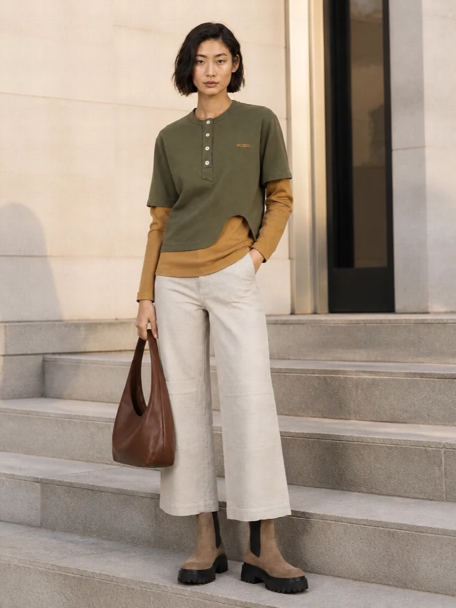 Grounded neutrals keep this city outfit easy but considered: a layered olive henley up top, stone utility trousers, and taupe lug Chelsea boots for traction and attitude. The cropped wide leg and chunky sole play nicely together, giving you volume where you need it and clean lines everywhere else. A soft chestnut hobo finishes the mix with just enough richness while staying firmly in the everyday zone.