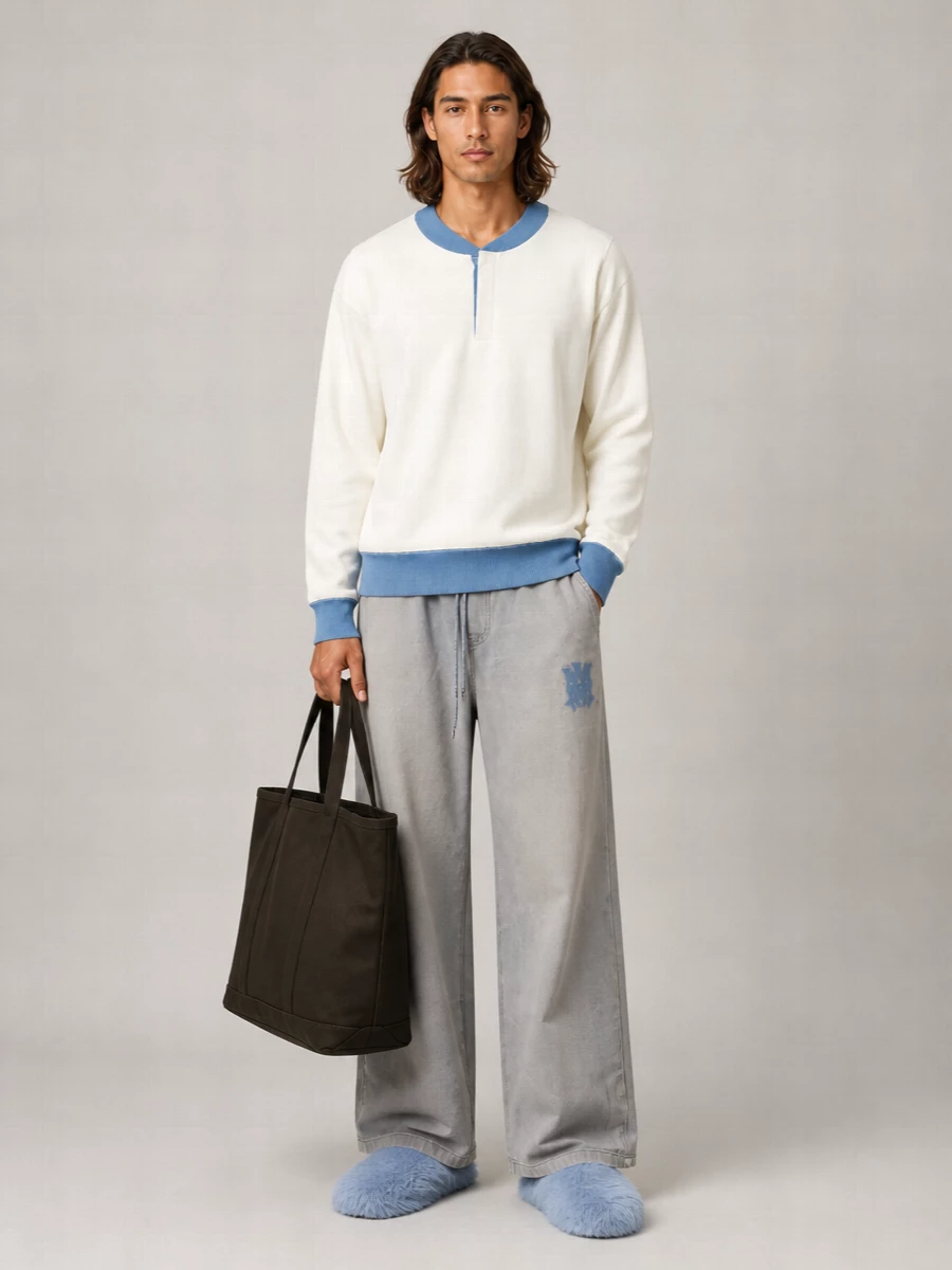 Powder-blue faux-fur mules and washed grey wide-leg trousers set an easy, skate-adjacent foundation that still feels sharply considered. The rugby-inspired long-sleeve ties in the blue and off-white story, while the oversized olive tote adds a grounded, utilitarian counterpoint. The result is soft, graphic streetwear that reads quietly fashion-aware rather than loud.