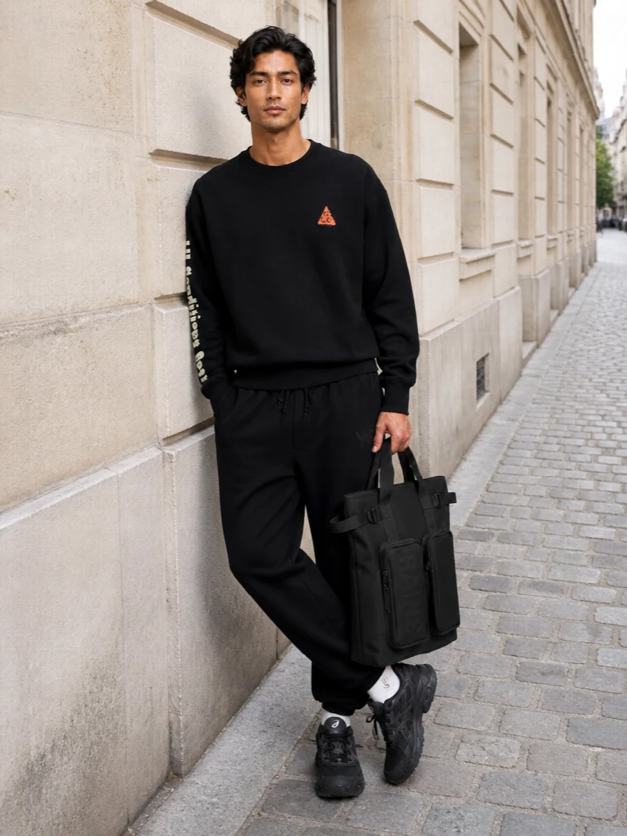 Keep it clean and technical with the ACG crew sitting over fluid black Y-3 track pants for a monochrome, trail-influenced city uniform. The black and grey Asics runners add low-key performance energy, while the matte Rains backpack keeps the whole story practical and sharp. Diesel’s logo socks are the small branded hit that finishes the sport-street mix without shouting.