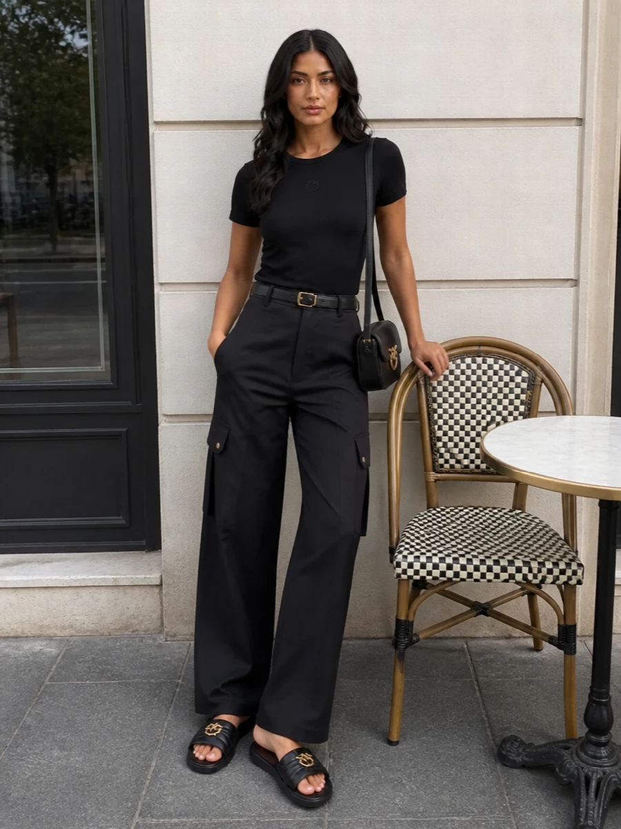 A black logo tee tucks neatly into high-rise charcoal cargos for a low-key, street-led silhouette that feels clean rather than slouchy. Padded black slides keep it relaxed and grounded, while a structured black crossbody and slim belt in matching gold hardware add just enough refinement for city days without disturbing the monochrome mood.