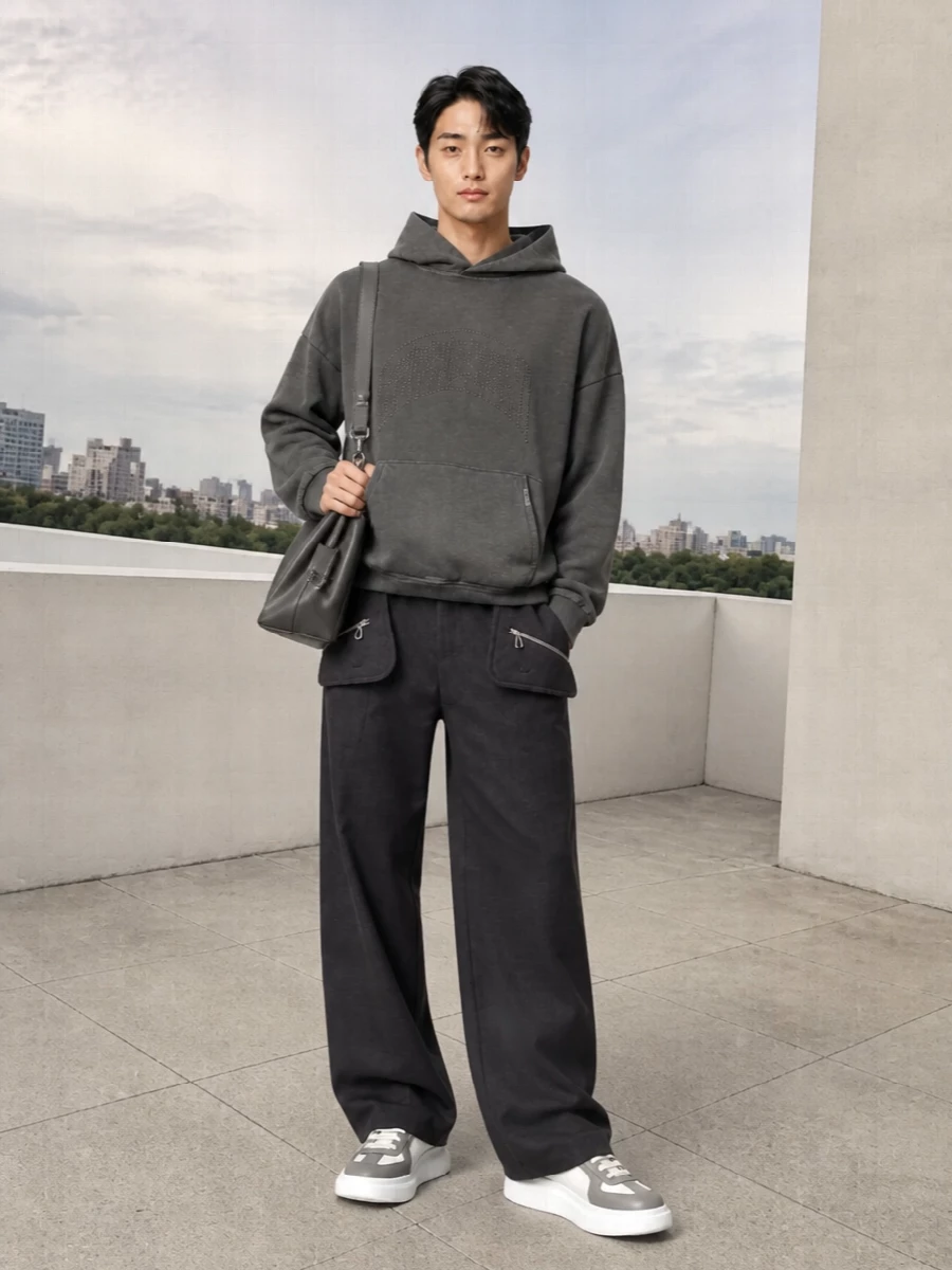 Charcoal and cool grey sit at the core here, giving the Balenciaga bag a tonal environment that feels modern and quietly assertive. The oversized hoodie relaxes the mood, while the wide Kiko trouser and sculptural McQueen sneakers keep the silhouette strong and directional rather than slouchy. It is streetwear for the city that still reads considered and luxury‑level up close.