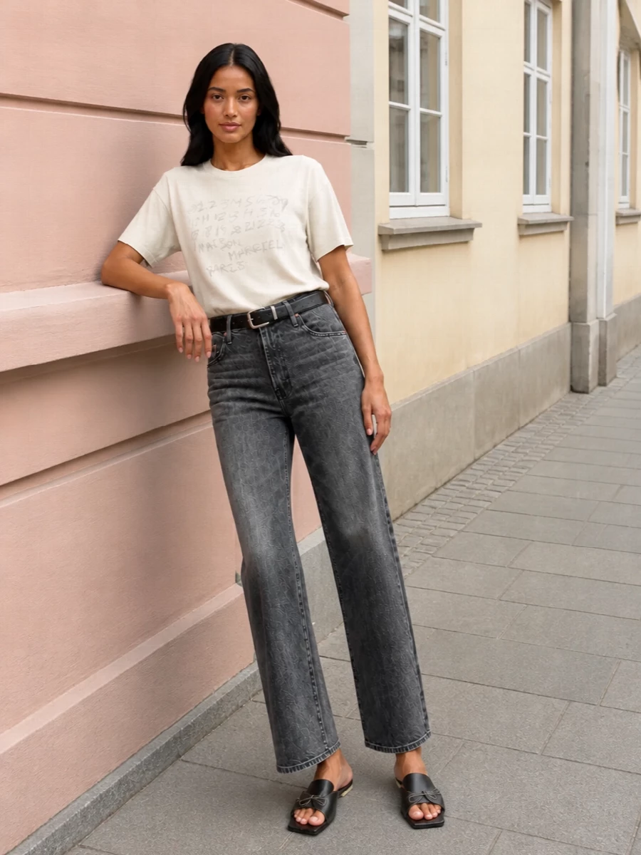 Washed charcoal denim sits with a relaxed Margiela tee for a clean, tonal base that feels easy but intentional. Square‑toe slides and a sculptural black tote keep the mood low to the ground and modern, while a slim black belt gives just enough structure at the waist. The result is quietly graphic and city ready without tipping into over-styling.