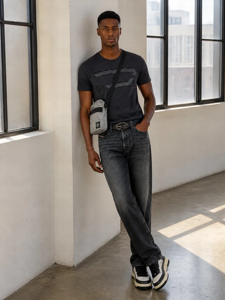 Charcoal tones run through the Diesel tee and washed-black denim, giving a tight, graphic base that feels distinctly urban without going heavy. Chunky low-top sneakers keep it grounded in street sport, while the Stone Island crossbody and subtle Diesel belt add just enough hardware and texture to feel considered. It is an easy, city-ready uniform built around dark neutrals and clean lines.