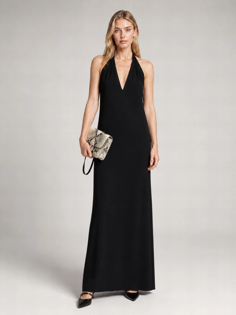 A black Totême halter maxi creates a long, uninterrupted column that lets the textured snakeskin clutch do the talking. The pointed black slingback keeps the line sharp and formal without adding visual noise. This path feels stronger than separates because the single, fluid silhouette better supports the bag’s sculptural hardware and quiet luxury attitude for evening events.