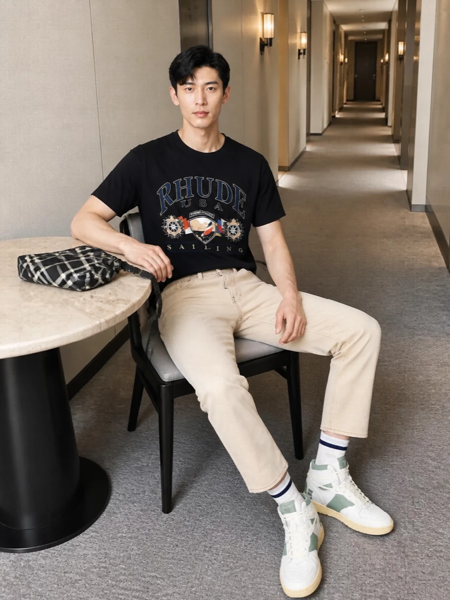 Rhude’s sailing tee sits over washed beige denim for a preppy, West Coast take on streetwear that feels more polished than gym-ready. The high-top courts and striped socks keep it rooted in sport, while the monochrome crossbody finishes things with a sharp, urban edge. It is an easy city uniform that still wears the collegiate crest attitude loudly on top and quietly everywhere else.